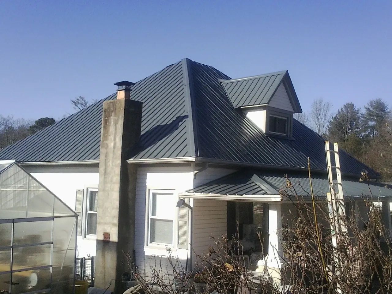 Dark blue standing seam metal roof on a white farmhouse with dormer — Slate & Tile Roof Repair by Roofing Brothers in Mongaup Valley