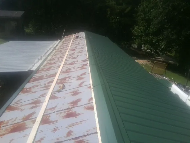 Old rusted panels beside newly installed green metal roofing — Wind Damage Roof Repair by Roofing Brothers in Mongaup Valley