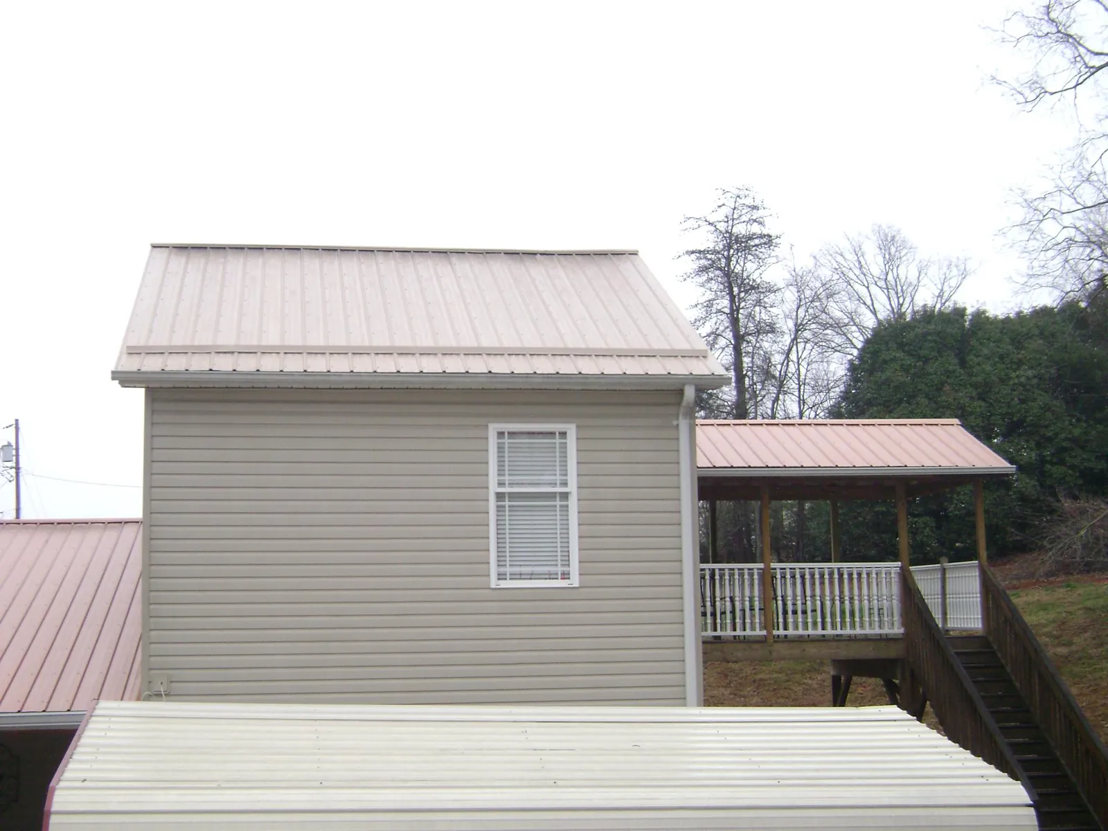 Tan metal roofs on a two story addition and attached porch, from a Roof Replacement job in Mongaup Valley