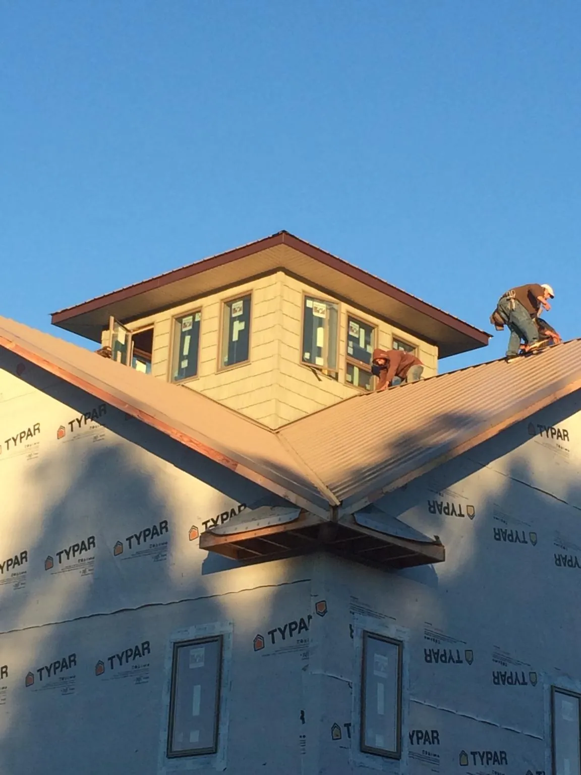 Roofers working around a rooftop cupola on a new metal roof at sunset — Roof Waterproofing in Mongaup Valley by Roofing Brothers